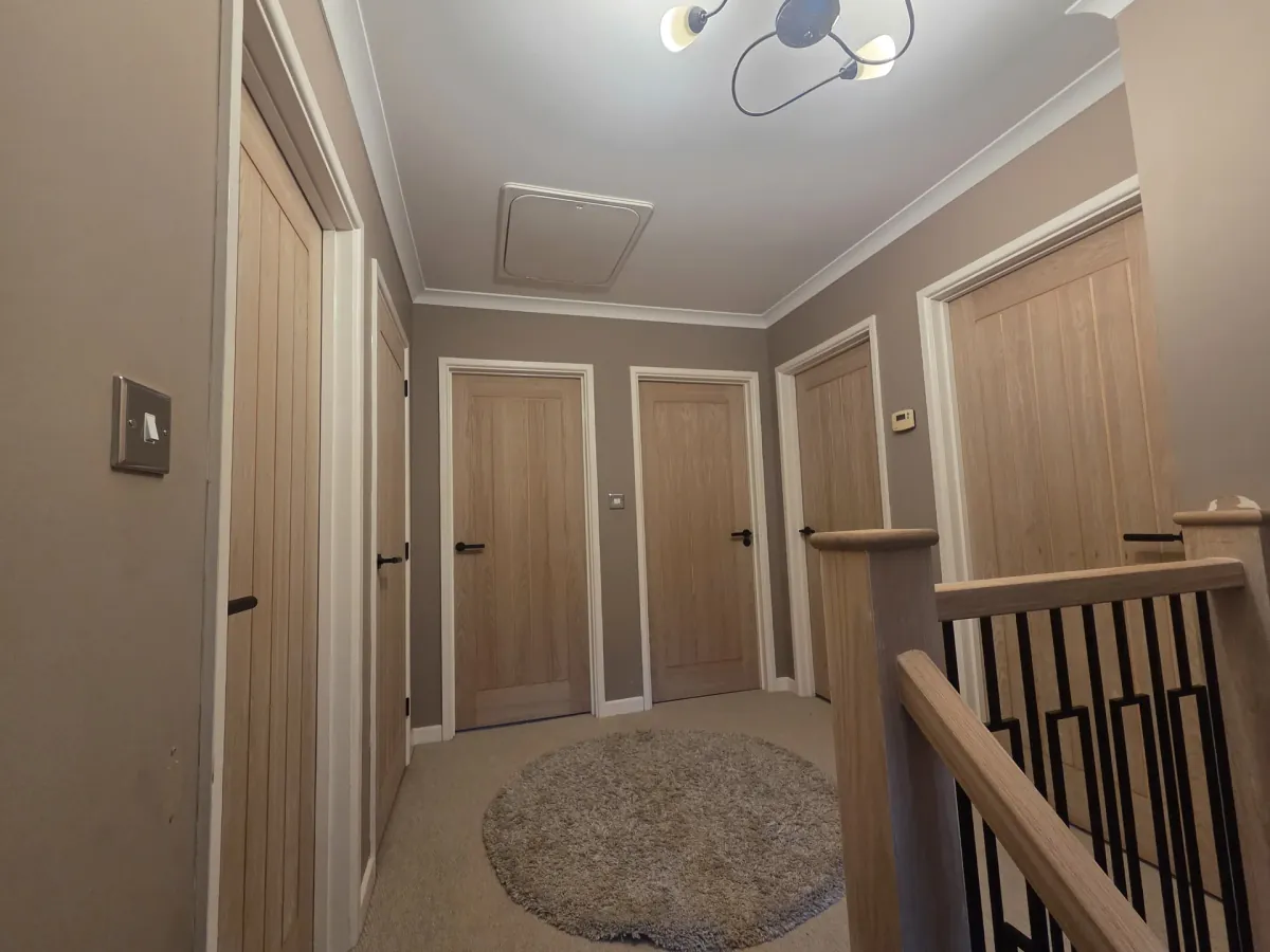 Completed upstairs landing with oak doors and modern lighting in Port Talbot